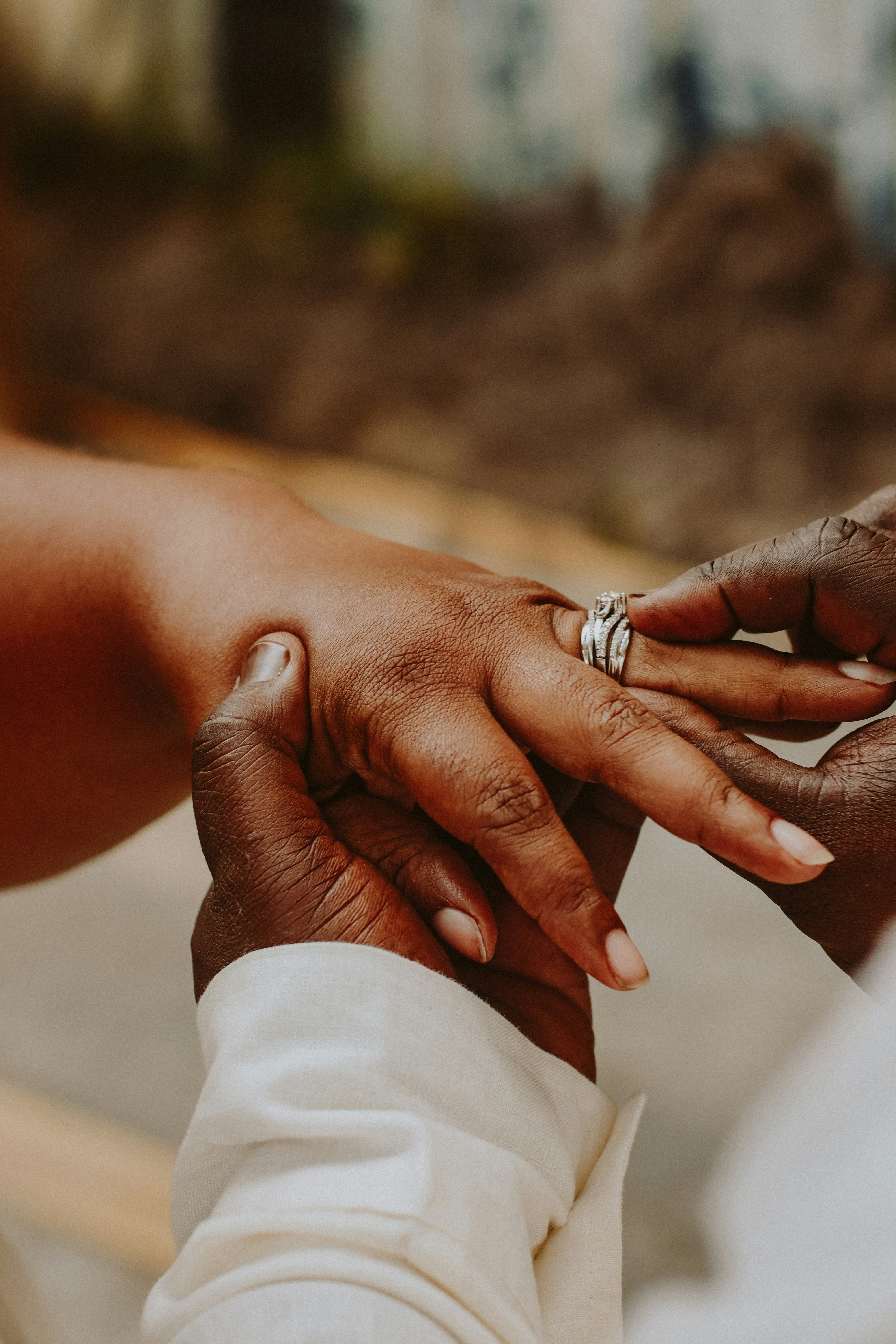Close-up of an engagement ring being placed on a hand.